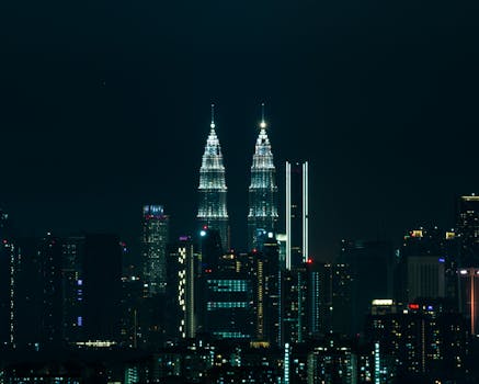 Breathtaking view of Kuala Lumpur's skyline at night featuring the iconic Petronas Towers illuminated against a dark sky.