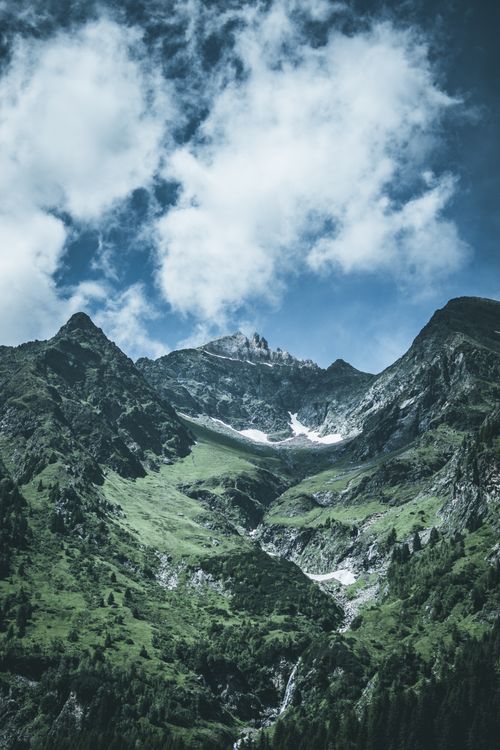 Free Explore the breathtaking views of a picturesque mountain range with green valleys and dramatic cloud formations. Stock Photo