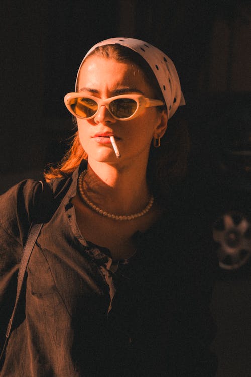 Woman with a Cigarette Posing in Black Shirt, White Headscarf and Retro Sunglasses