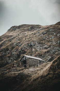 崎岖的山景中坐落着一座孤独的小屋，展现着大自然的美丽