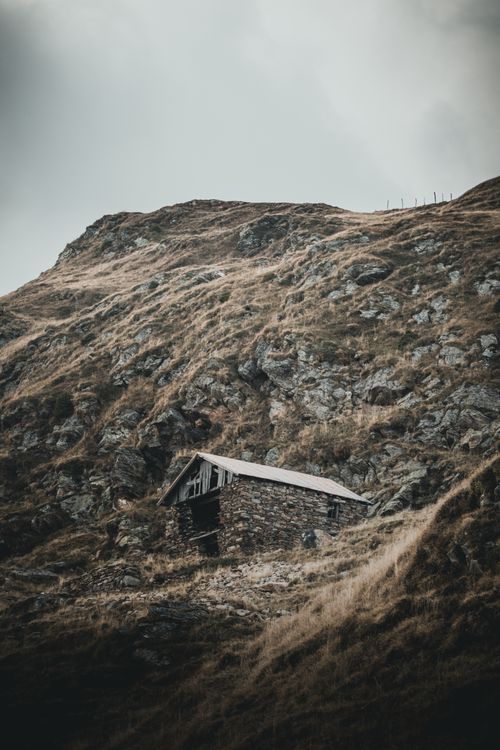 Free A solitary cabin nestled in a rugged mountain landscape, showcasing nature's beauty. Stock Photo