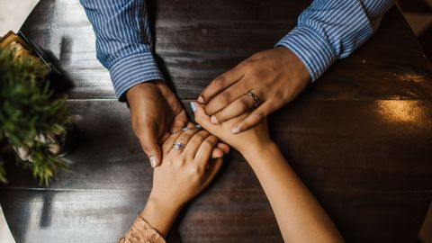A couple holding hands on a wooden table, expressing love and connection.