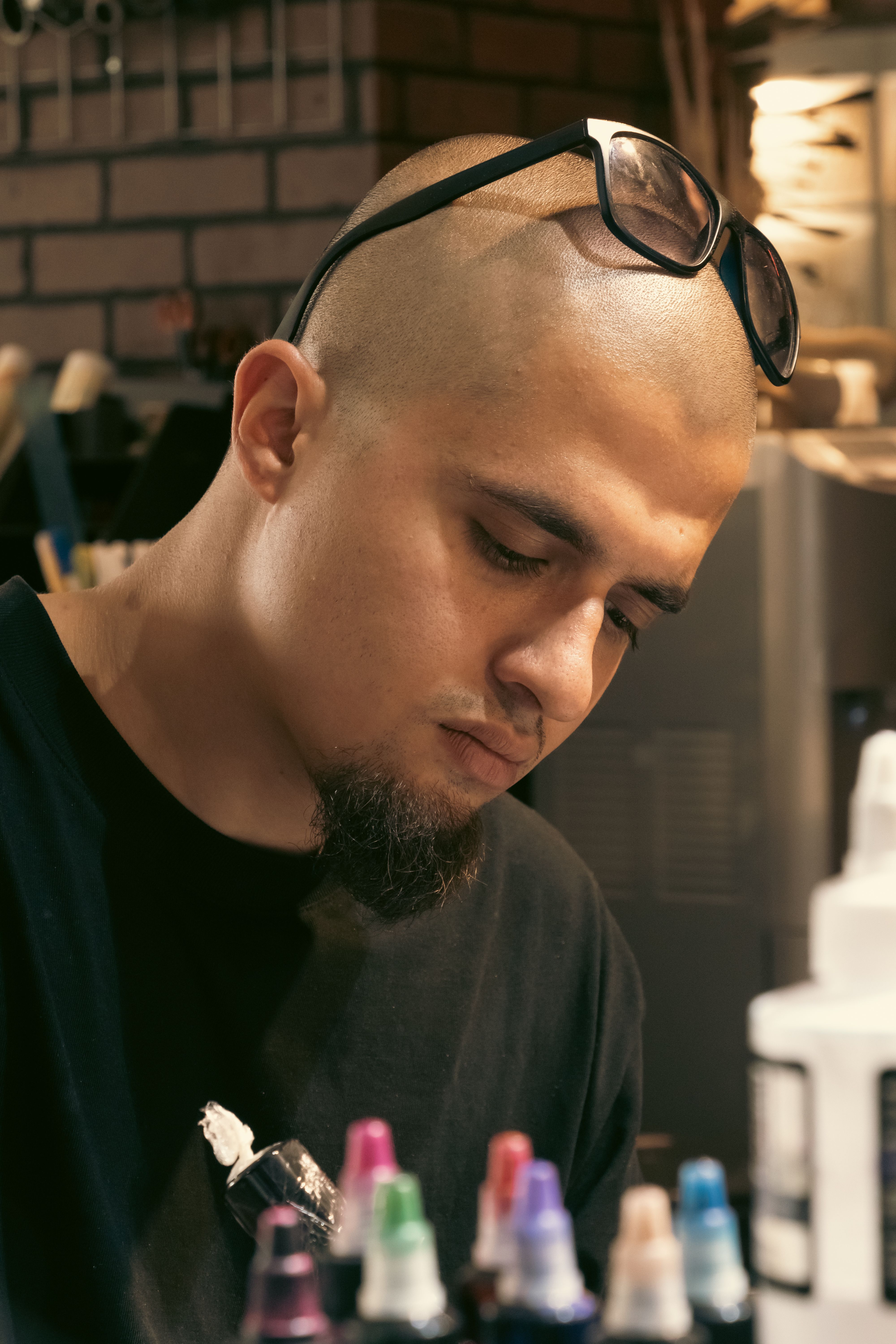 Portrait of a bald tattoo artist focused on work in a studio setting in Türkiye.