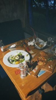 A cozy cafe table scene with remnants of a meal, including salad and appetizers.