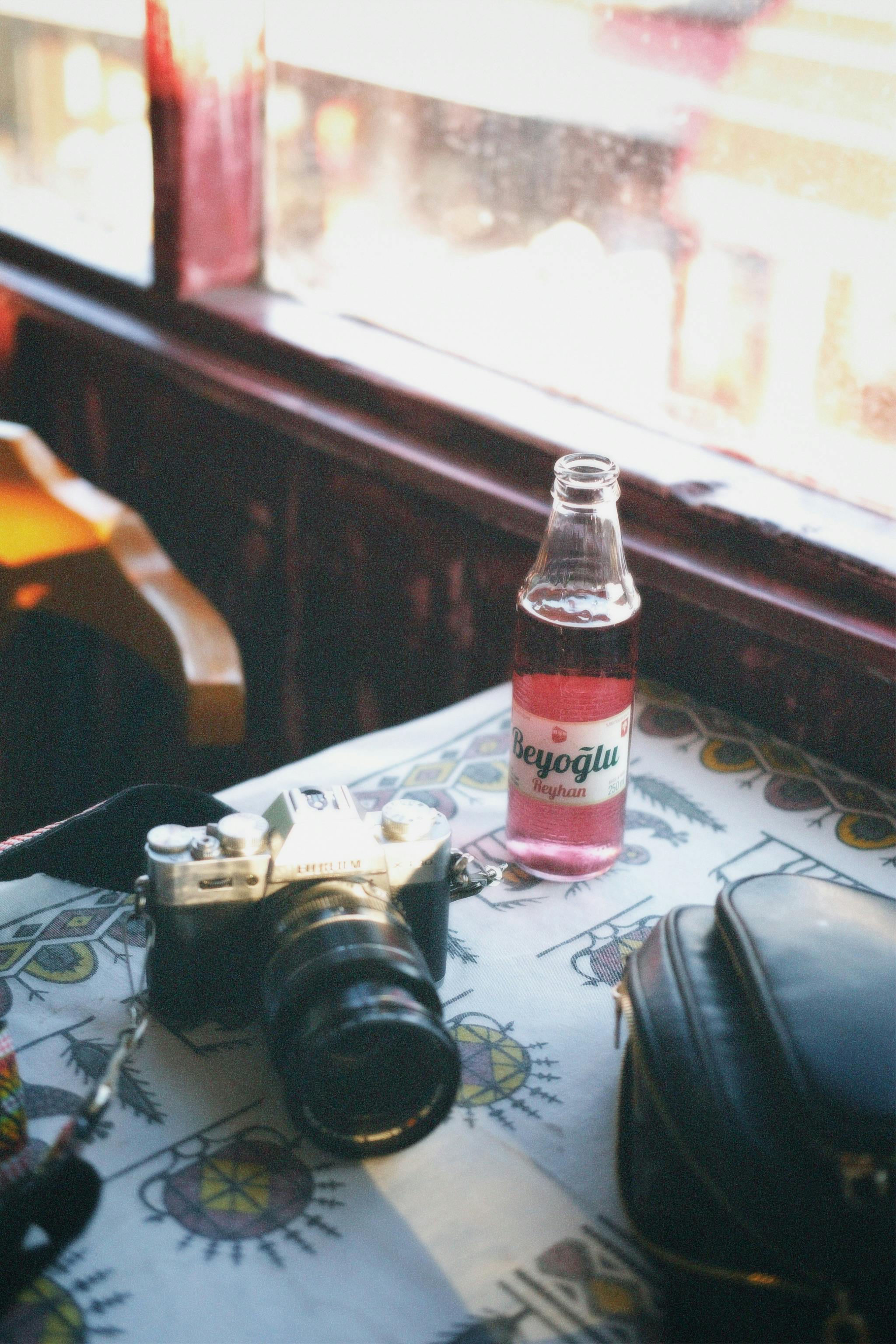 Camera and Bottle of Beverage on Table · Free Stock Photo