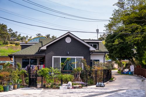 Free A charming suburban house with a lush front garden and laundry hanging outside on a sunny day. Stock Photo