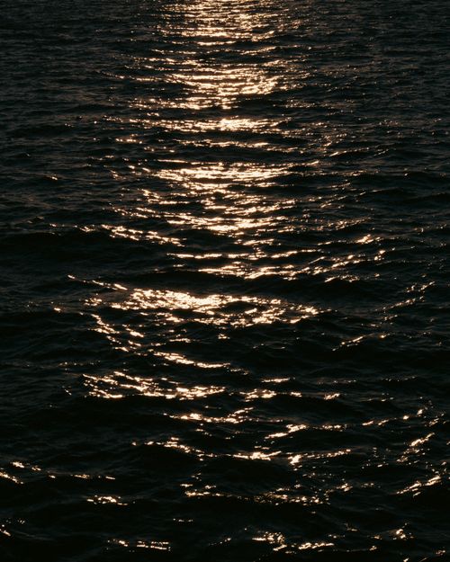Free The warm glow of a sunset reflected on the tranquil sea waters. Stock Photo