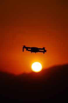 A striking silhouette of a drone flying against a vibrant sunset sky in Aladağ, Türkiye.