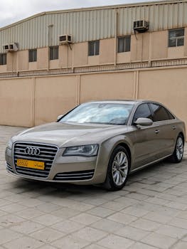 Audi sedan parked urban setting in Salalah, Oman. Sleek grey exterior against industrial background.