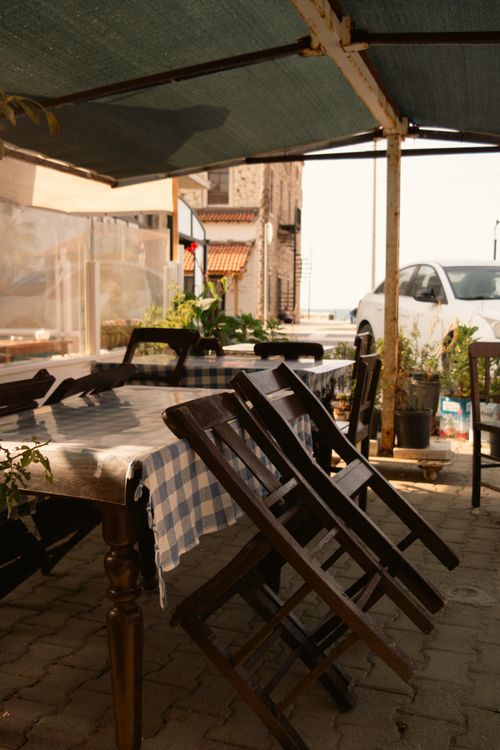 Free Charming outdoor patio setup with wooden chairs, a checkered tablecloth, and a sunny ambiance. Stock Photo