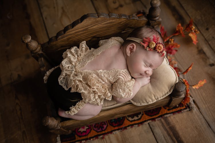 Newborn Sleeping On A Wooden Bed And A Pillow