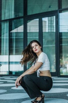 Stylish woman in a tied crop top posing outside a modern building.