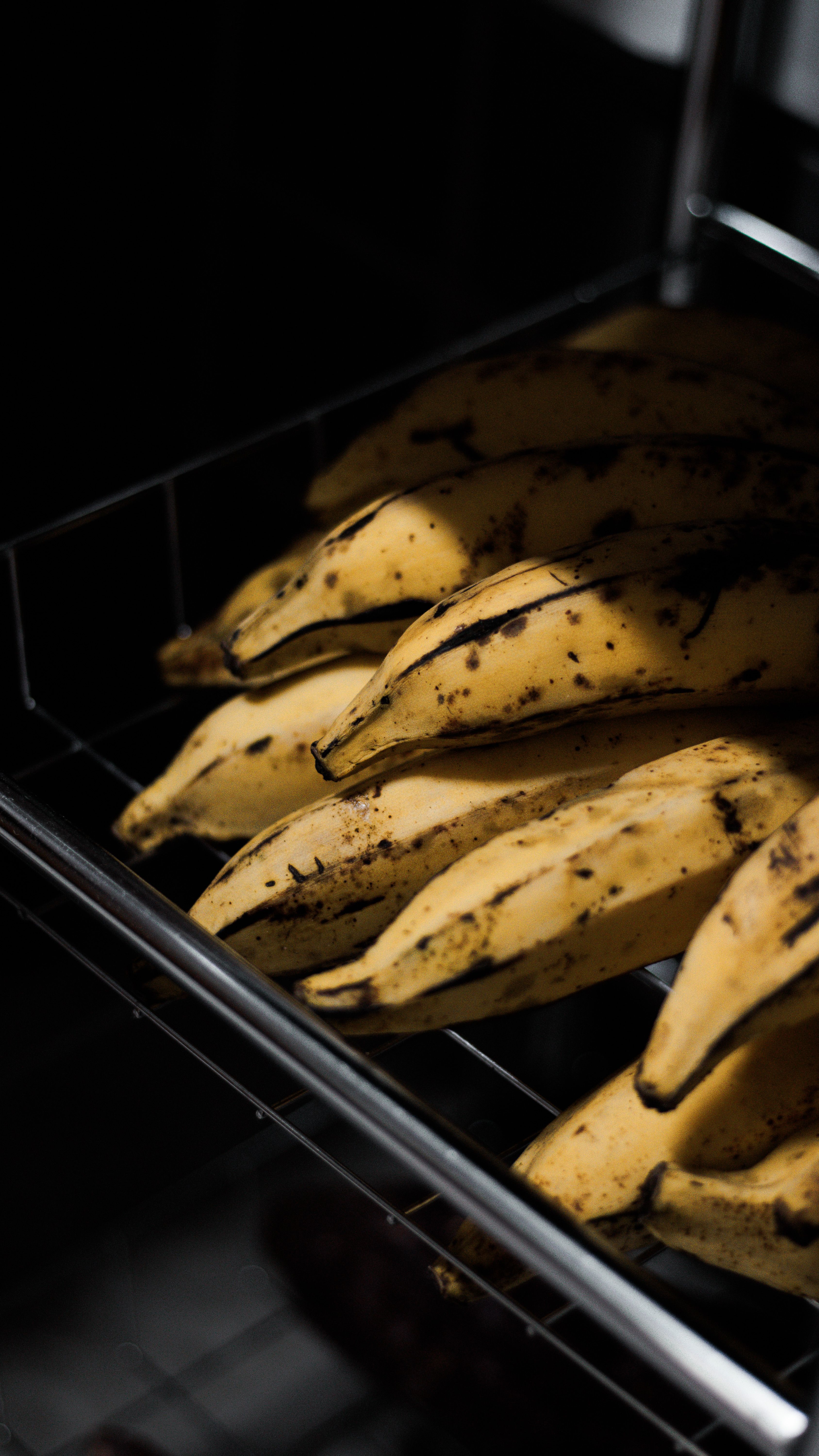 Fotomural Primer plano de plátanos maduros con manchas oscuras en un ambiente de cocina, ofreciendo textura y frescura.