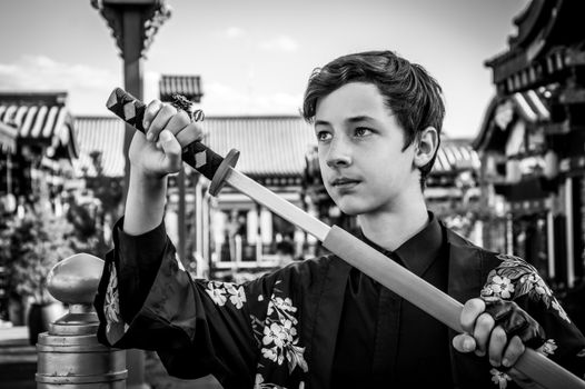 Young boy in traditional setting practicing martial arts with a sword, showcasing focus.