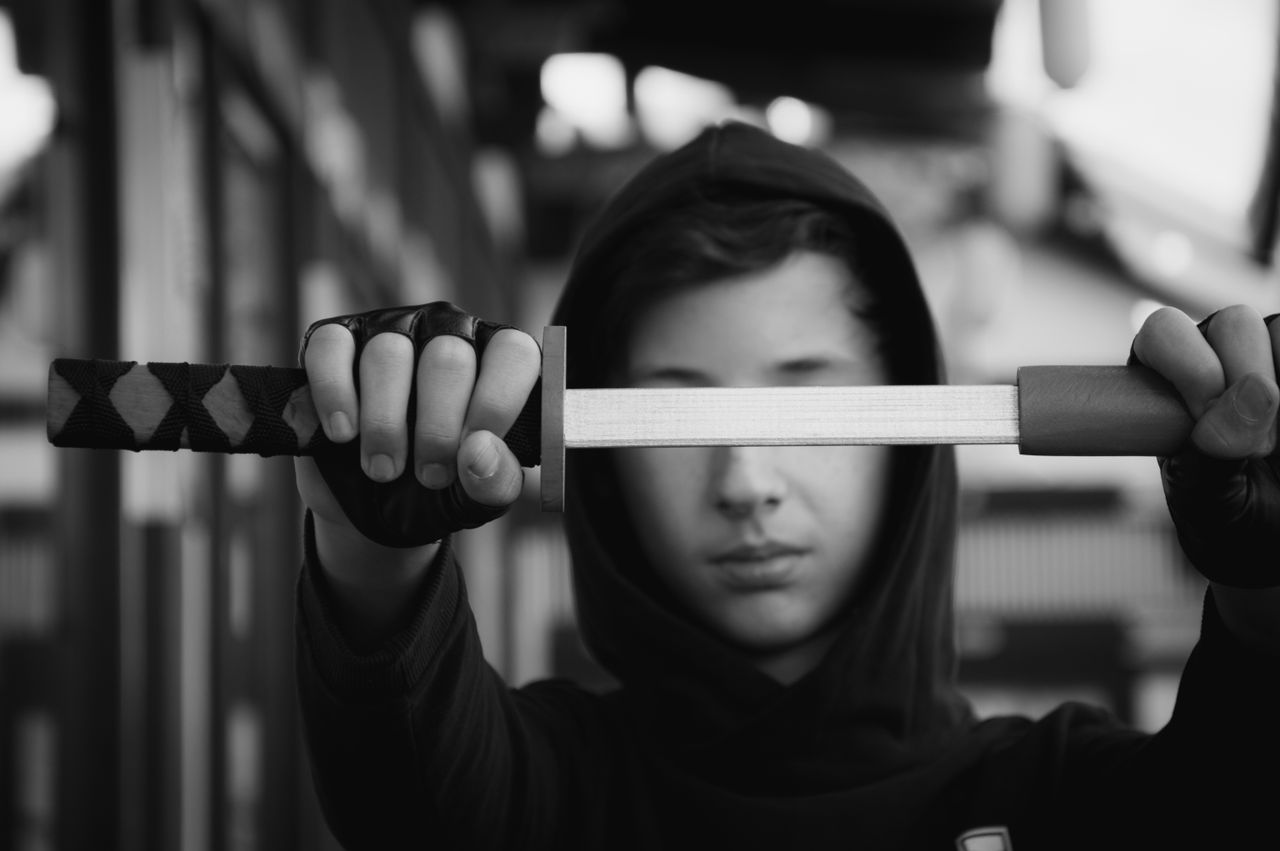 black and white image of a teenager holding a katana focused expressio