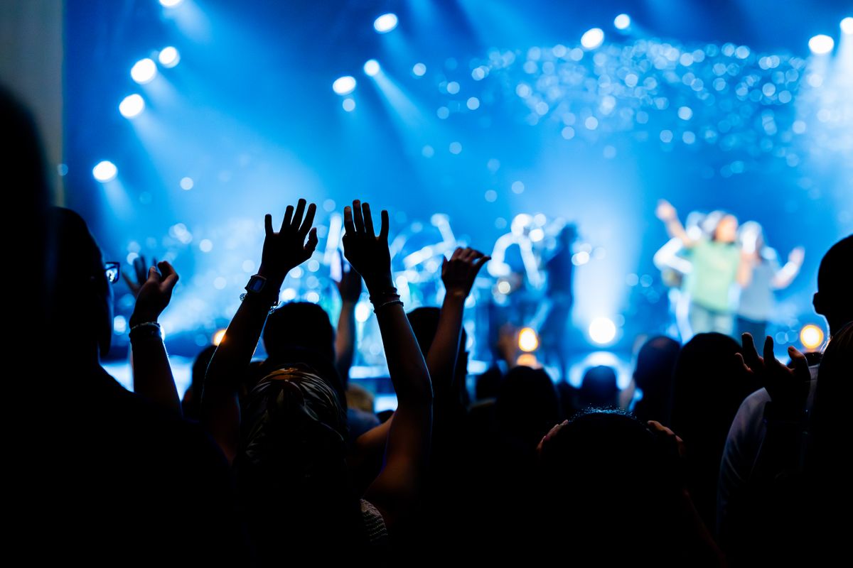 A concert crowd with hands raised, enjoying a live music performance