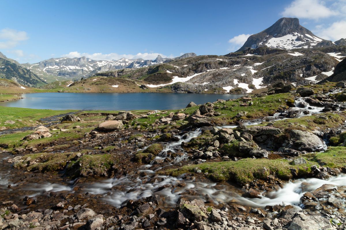 A high glacial lake and mountain stream below the Pyrenean peaks