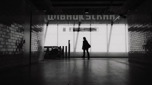 Free Black and white silhouette of a person in an urban train station corridor. Stock Photo
