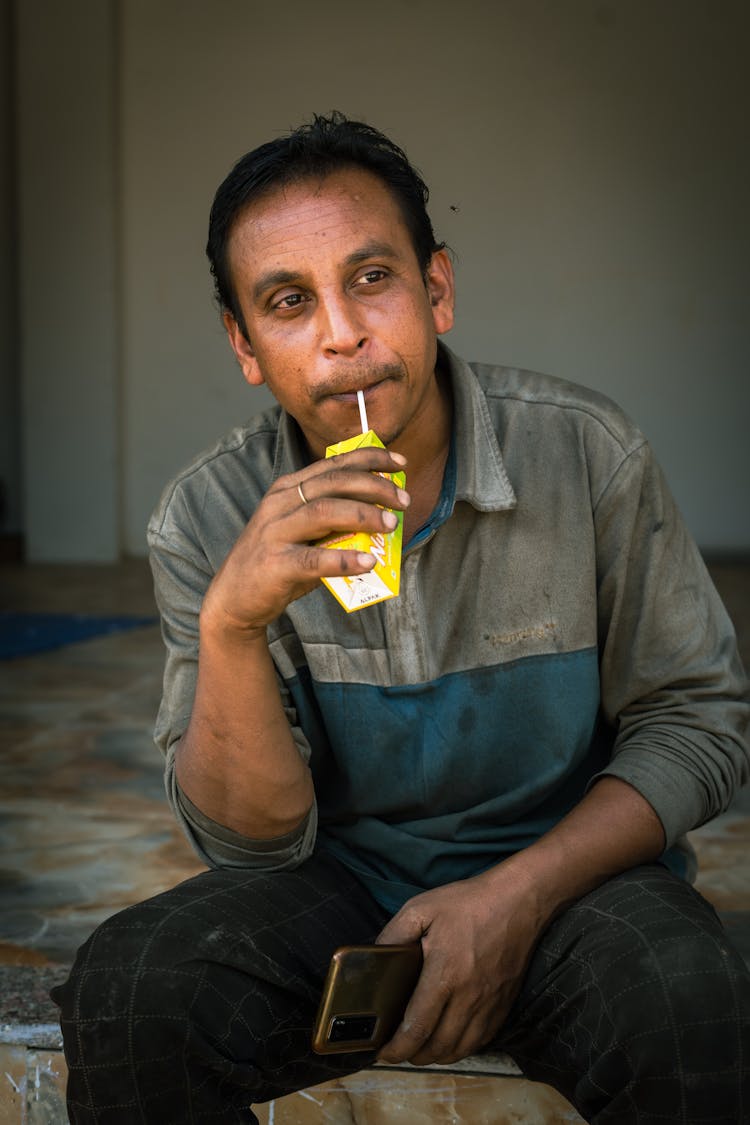 Man Drinking A Juice Box On The Porch During A Break