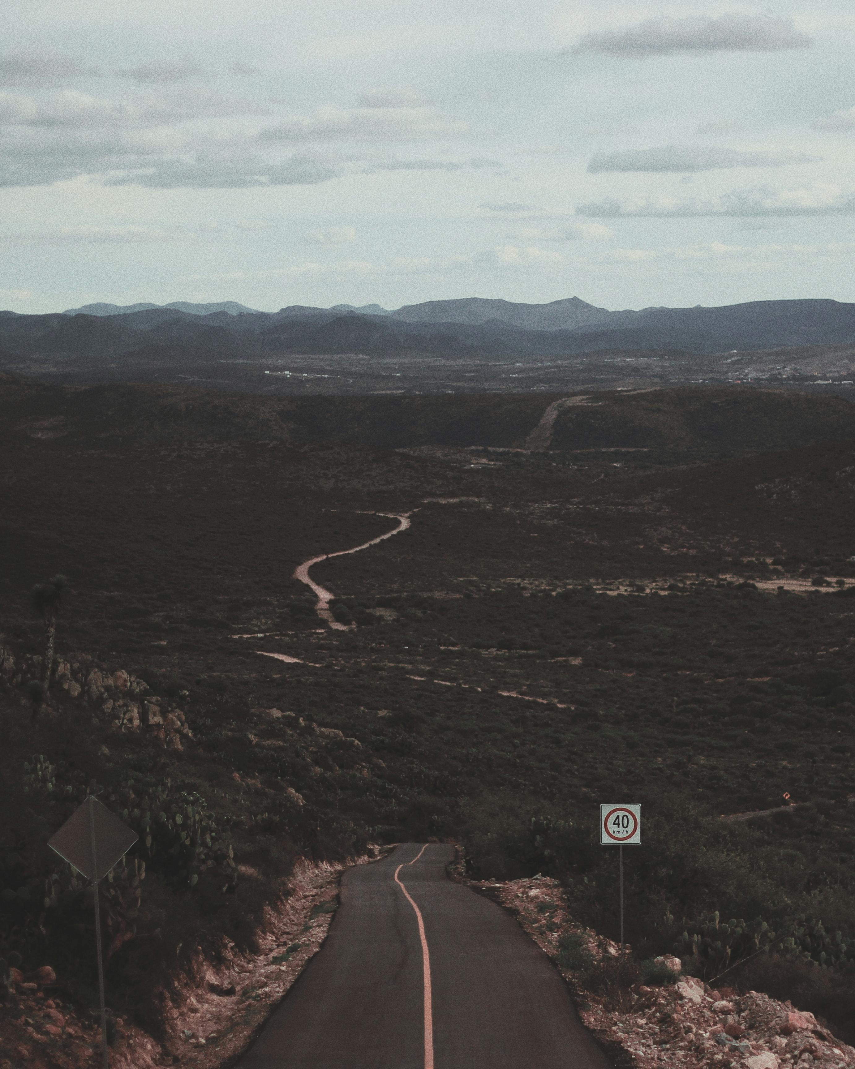 天空多云，蜿蜒的道路被山脉和开阔的景观所环绕