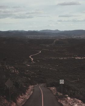 天空多云，蜿蜒的道路被山脉和开阔的景观所环绕