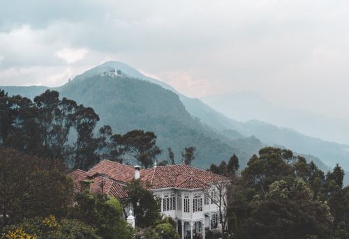 Free Charming Casa Santa Clara nestled in lush Colombian mountains with misty landscape. Stock Photo