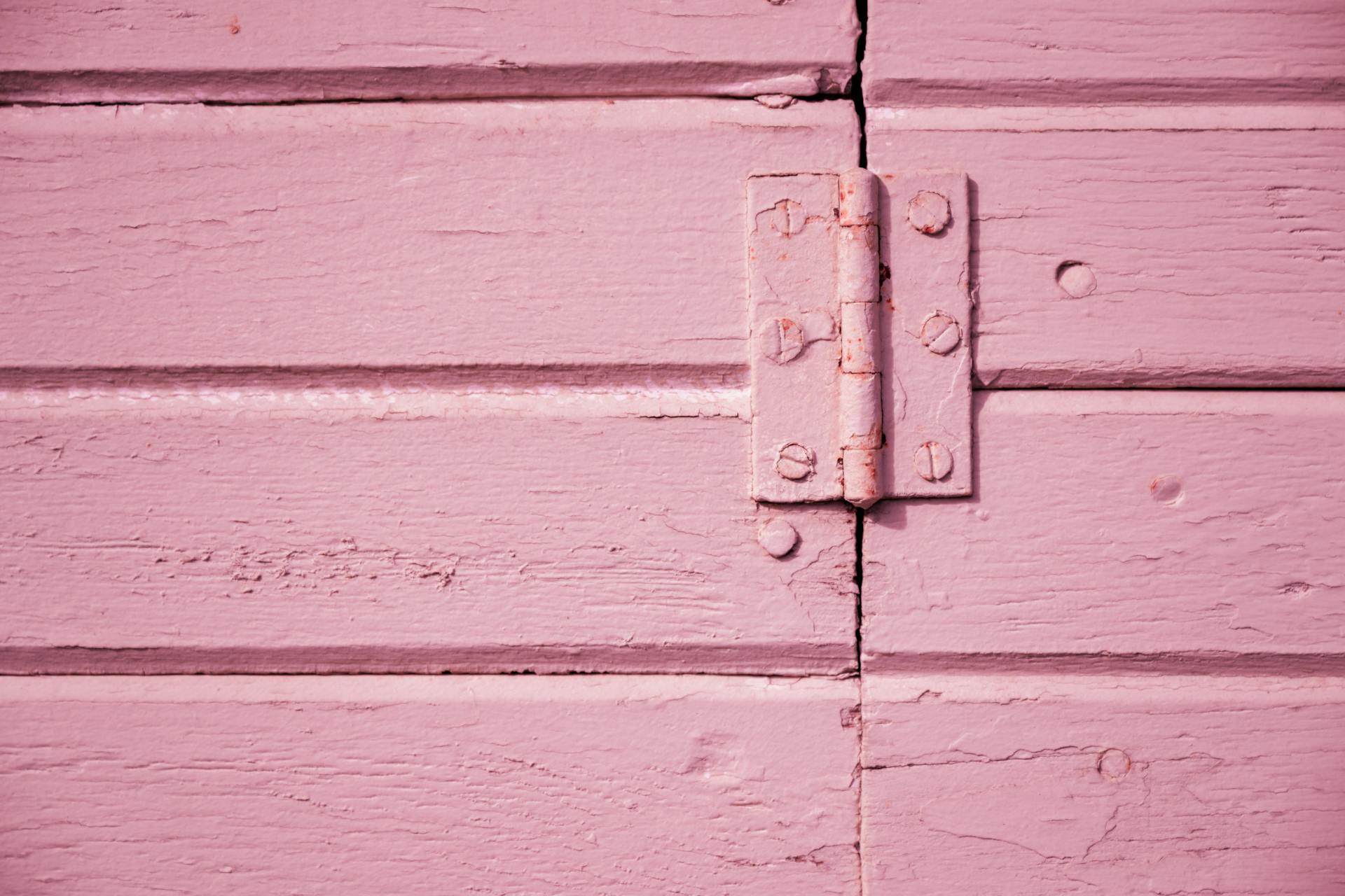 A detailed shot of a pink wooden hinge showcasing texture and color contrast.