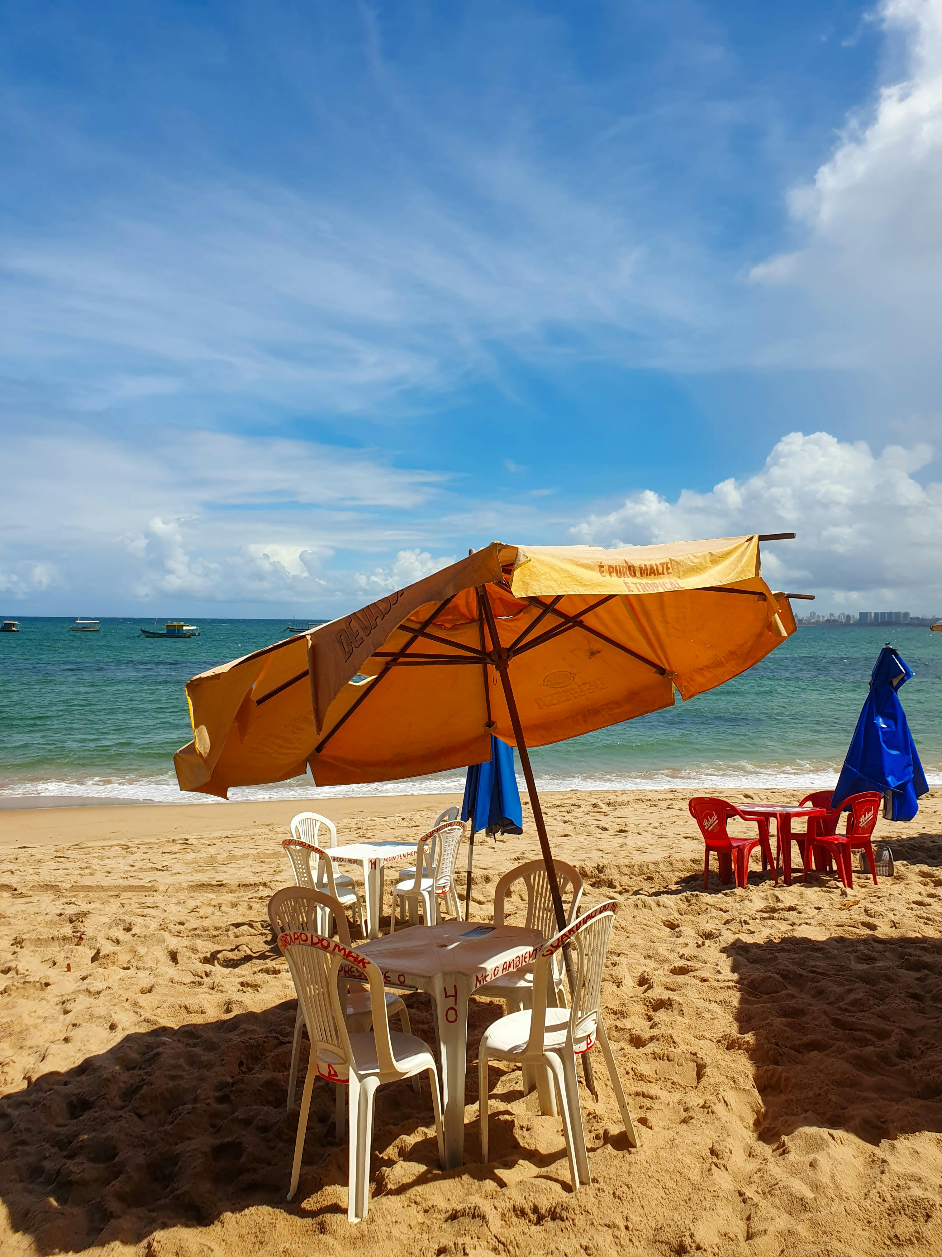 Plastic Tables and Chairs Under Umbrellas on the Beach · Free Stock Photo