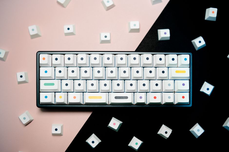 Top view of a mechanical keyboard with unique dot keycaps on a geometric background.
