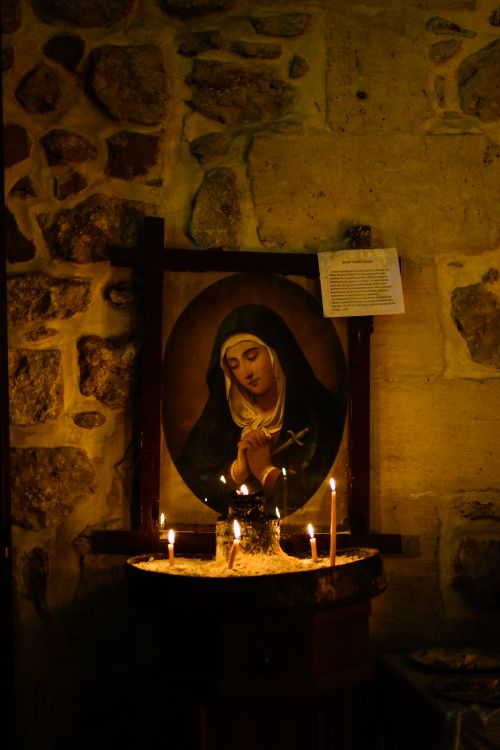 Free A serene candlelit scene in an ancient stone church featuring religious art, evoking peace. Stock Photo
