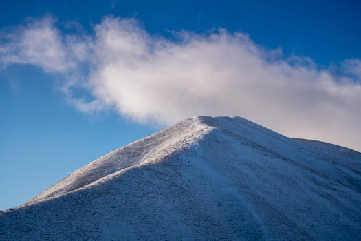 白雪覆盖的山峰映衬着柔和的云层，与充满活力的蓝天构成壮丽景色