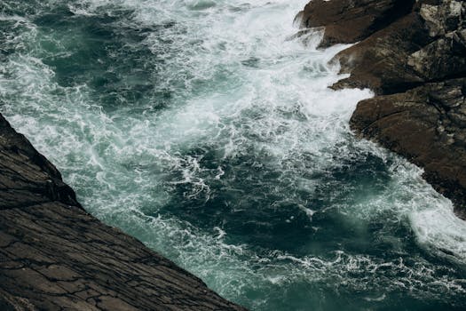 A powerful view of ocean waves crashing against the rugged rocky coastline at Mizen Head, Ireland.