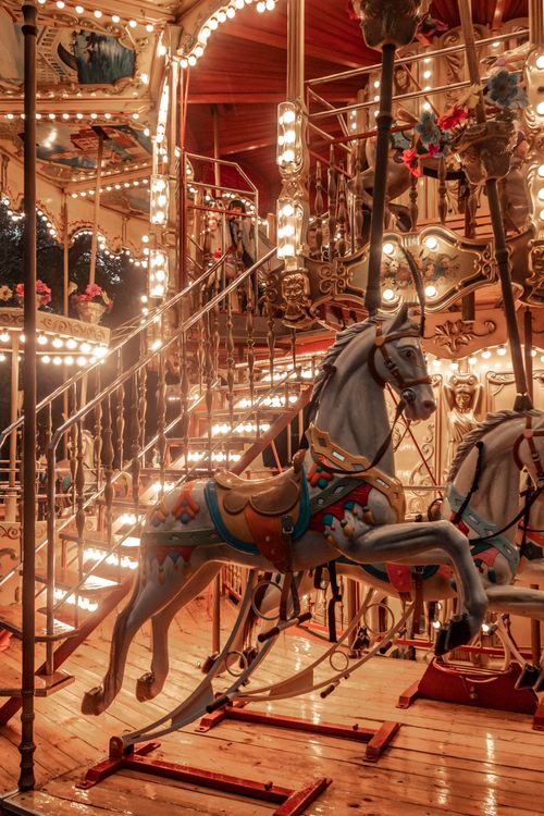 Free Charming, lit-up vintage carousel with detailed horses and ornate design at night. Stock Photo