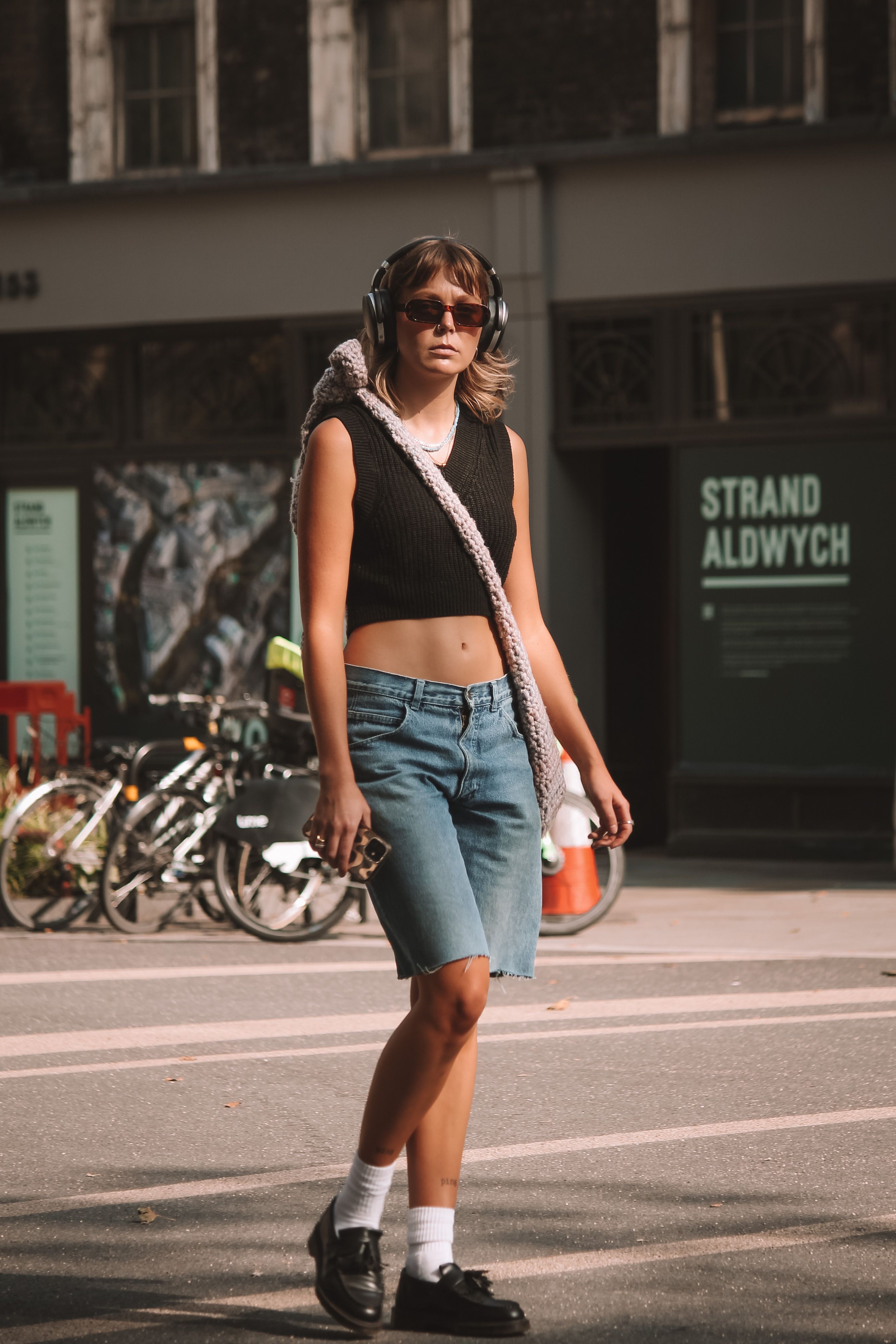 Jovem mulher com roupas de verão modernas caminha pela rua da cidade de Londres.