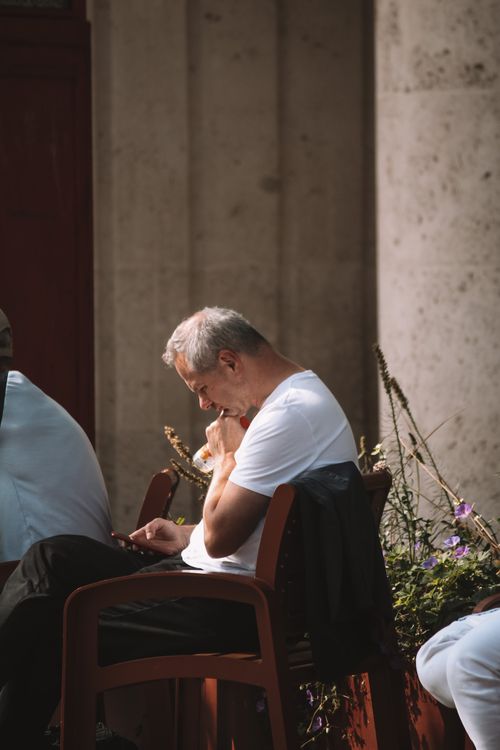 Free A tranquil scene of an elderly man enjoying a quiet moment at an outdoor cafe in London, England. Stock Photo