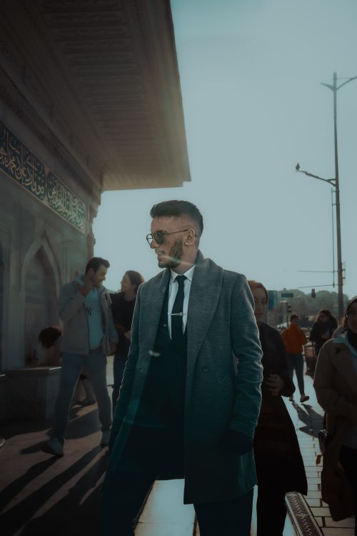 Free Elegant man in a suit and coat walking through a busy street in Istanbul, showcasing urban style. Stock Photo