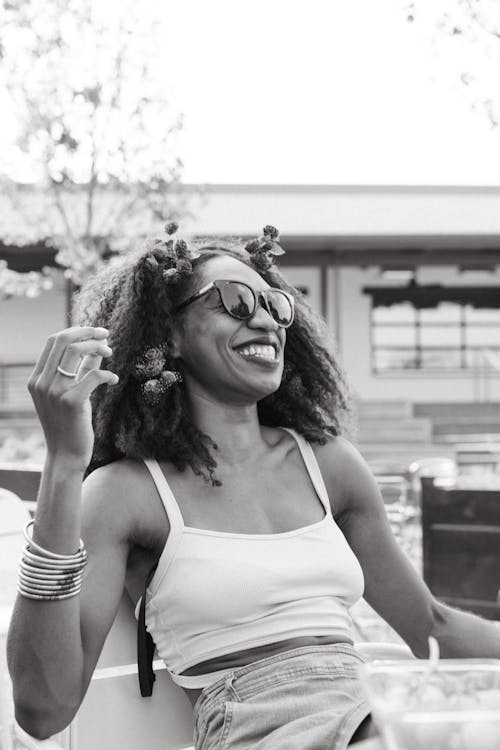 Grayscale Photo of a Laughing Woman with Flowers in her Curly Hair