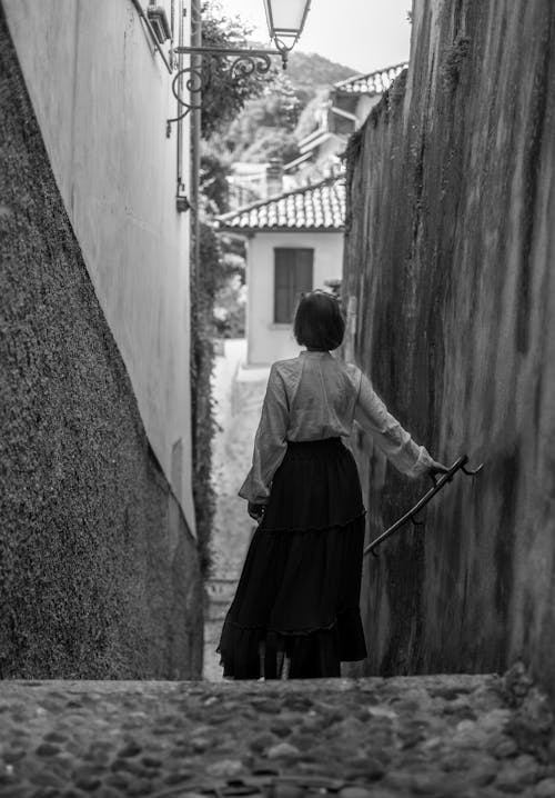 A Woman Walking Down the Stairs in a Narrow Alley 