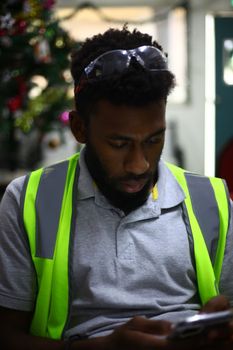 A young man in safety gear using a smartphone indoors.