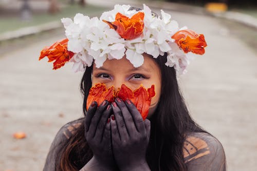 Woman with Tattoos and Holding Flowers Petals on Face