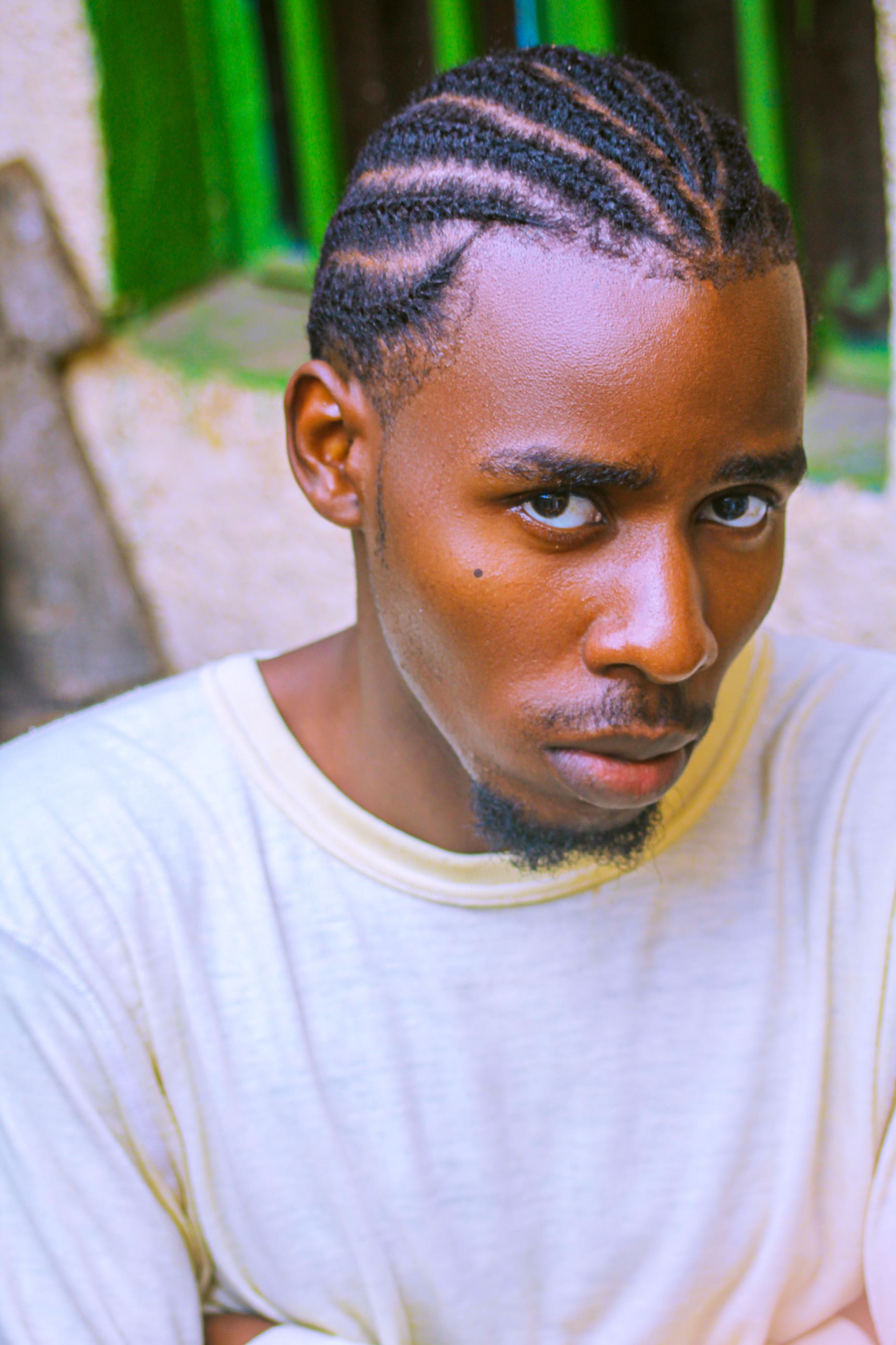 Close-up portrait of a young man with cornrow hairstyle and beard in Kigali, Rwanda.
