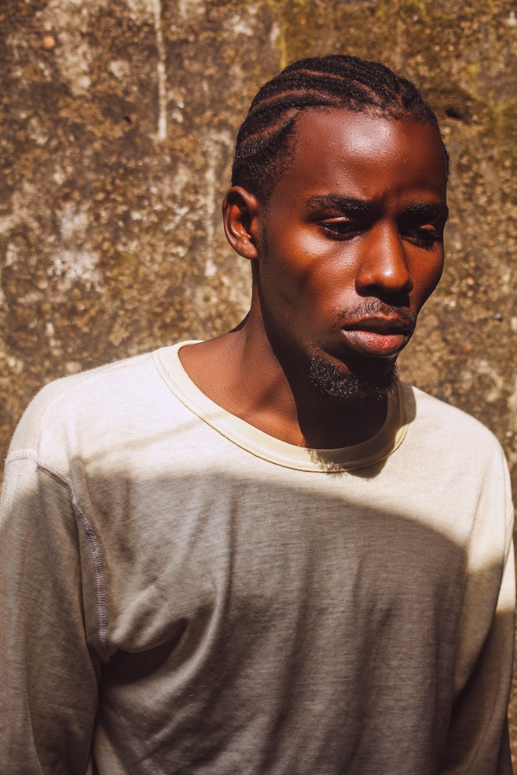 Sunlit portrait of an adult man standing outside in Kigali, Rwanda, wearing a white shirt.