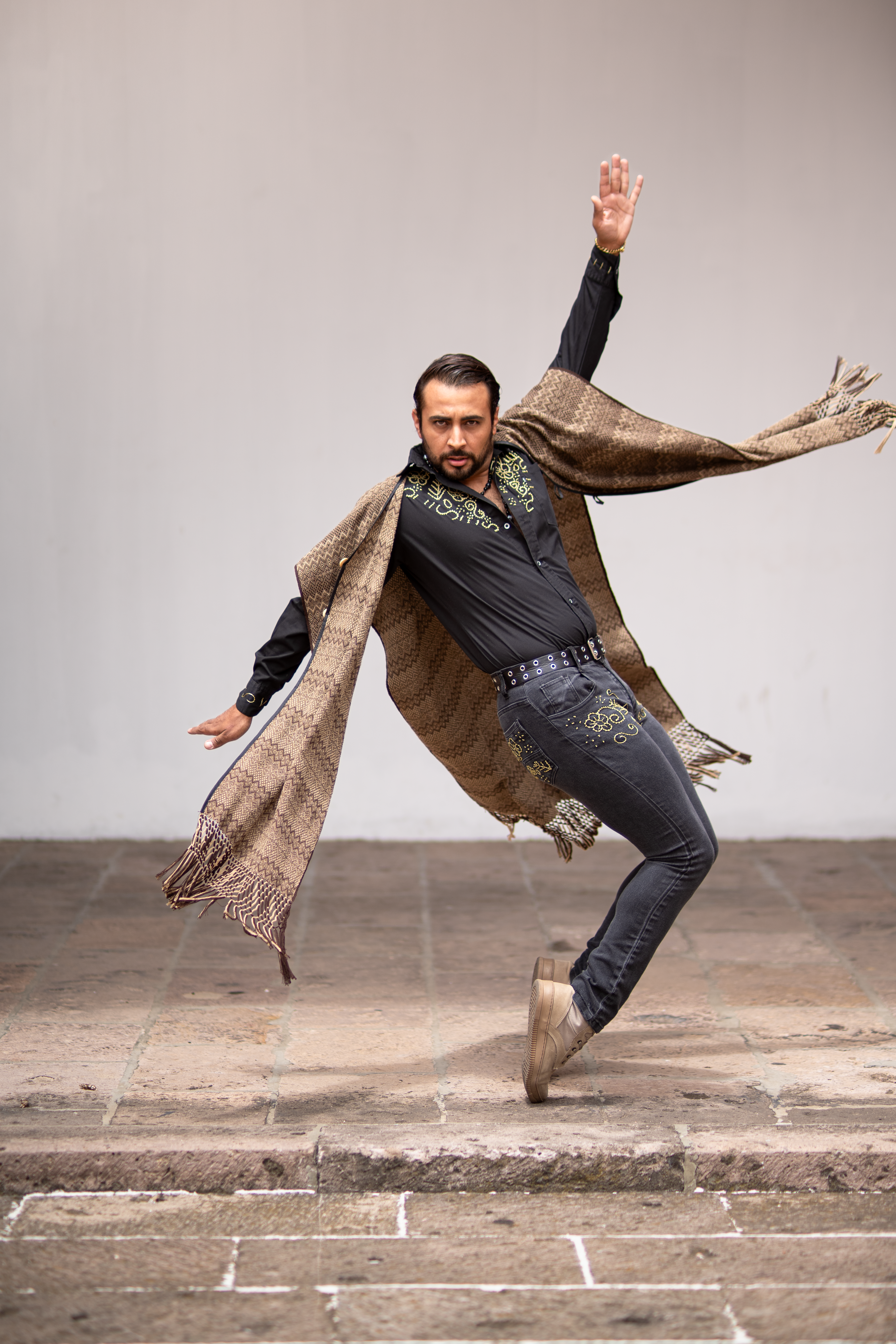 A stylish man strikes a dynamic dance pose wearing traditional Mexican attire in Morelia.