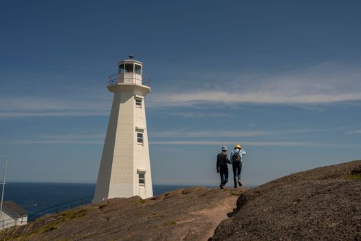 Couple walking near Cape Spear Lighthouse with scenic ocean views.