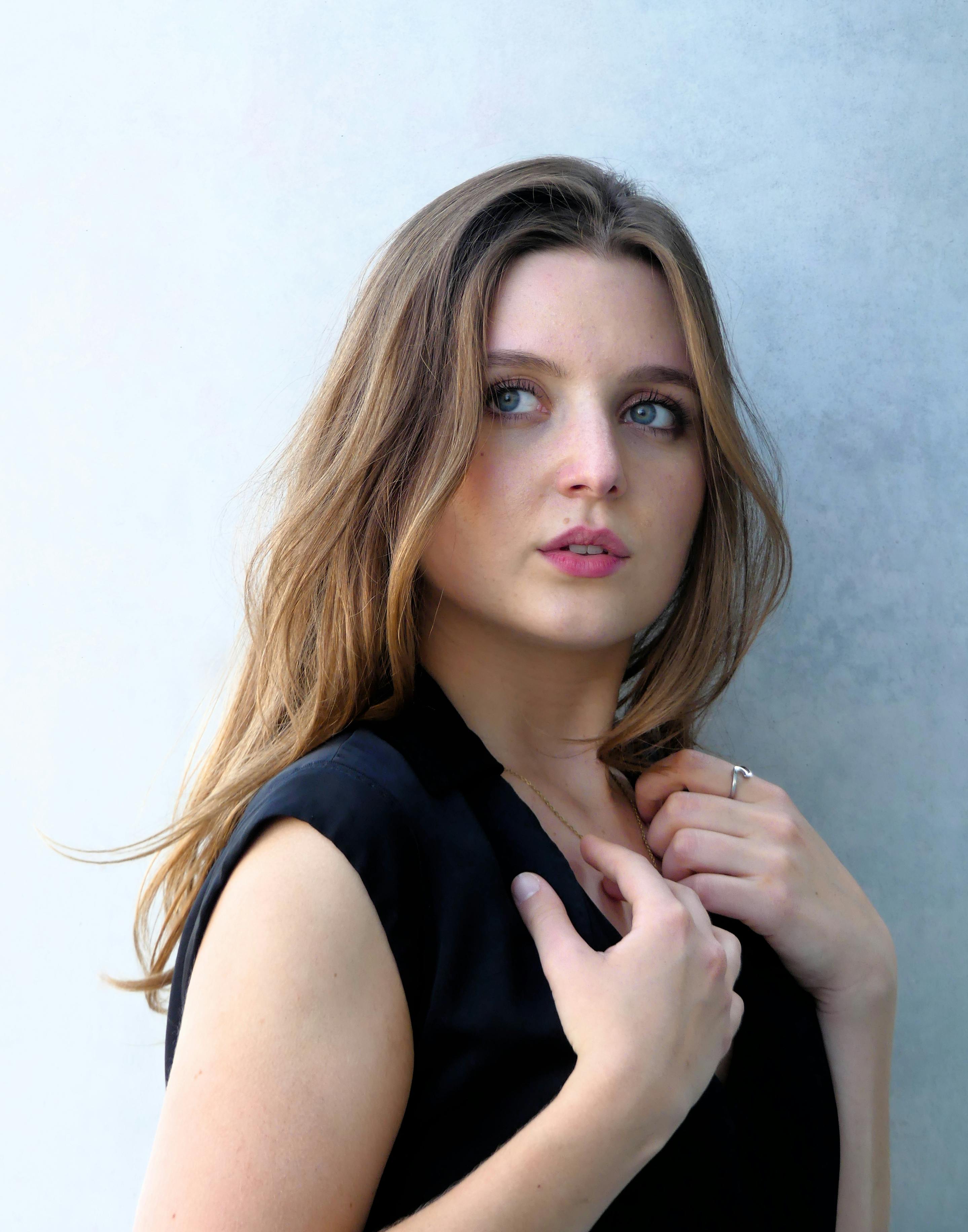 Portrait of a woman with long brown hair against a gray background, exuding grace and poise.
