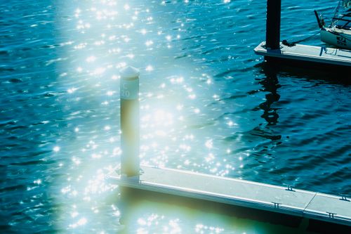 Free A marina with sparkling reflections of sunlight on the water, showcasing a serene and bright atmosphere. Stock Photo