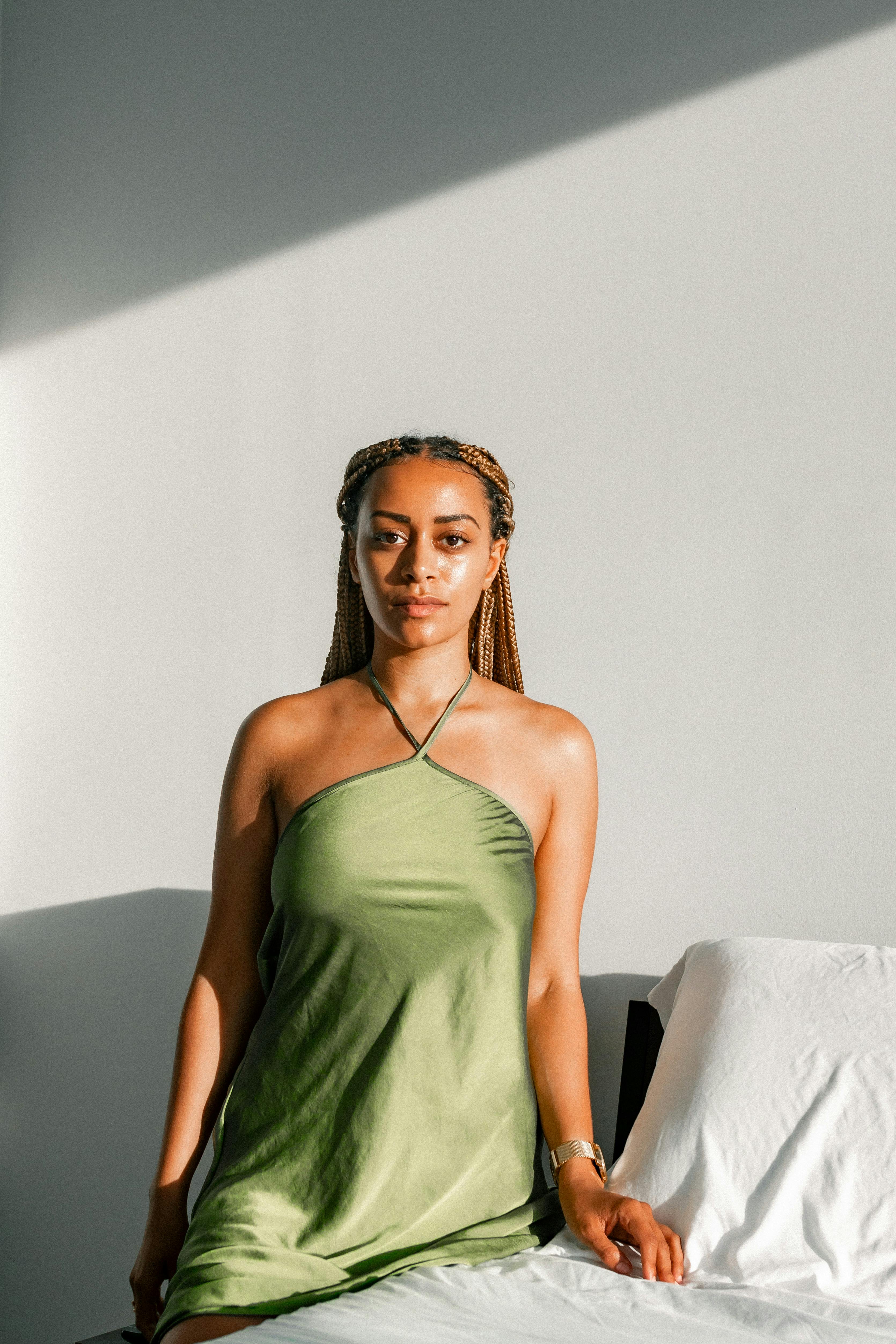 Elegant portrait of a woman sitting in a green dress with soft sunlight.