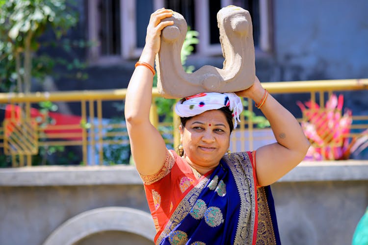 Woman In Traditional Clothing Holding Item On Head