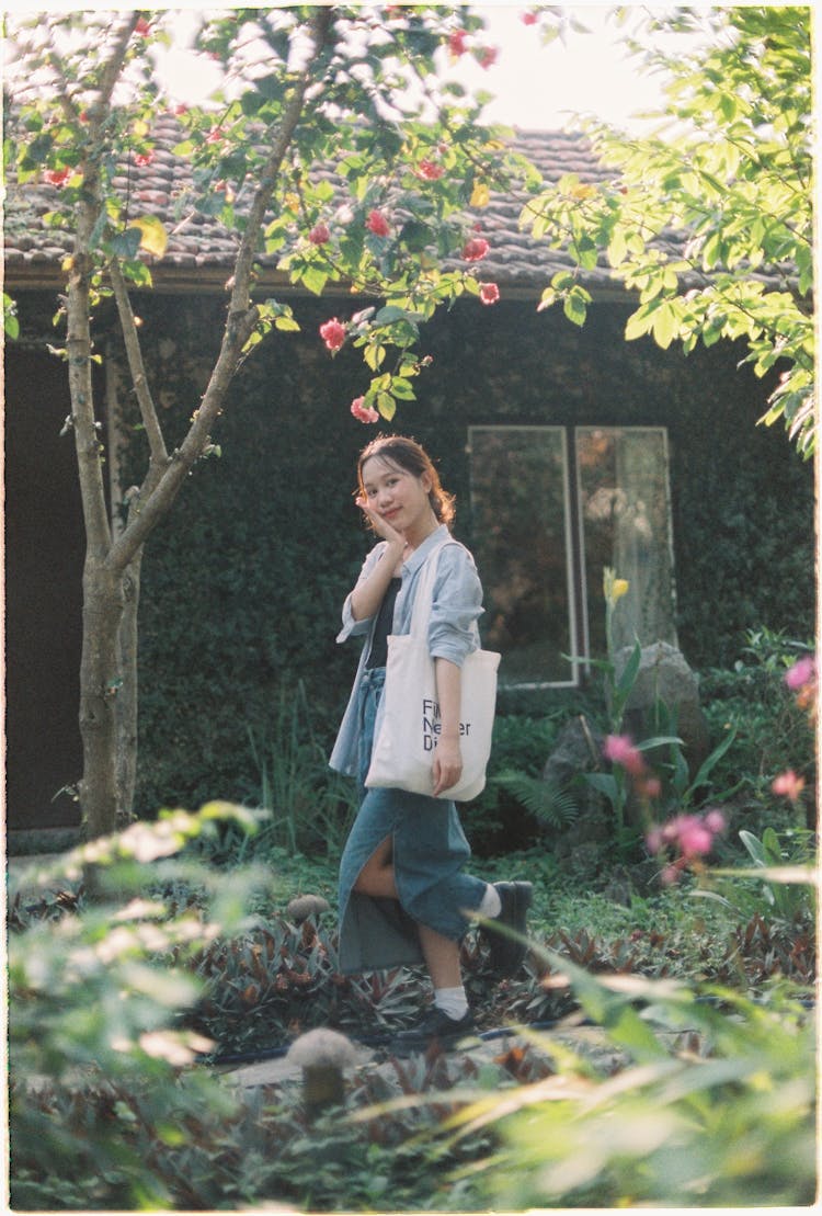 Asian Young Woman Walking In Green Garden Near House