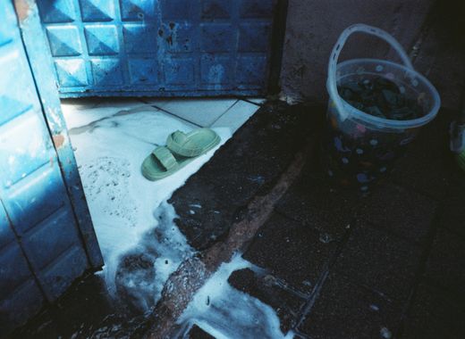 Flooded entrance with a bucket and slippers in standing water